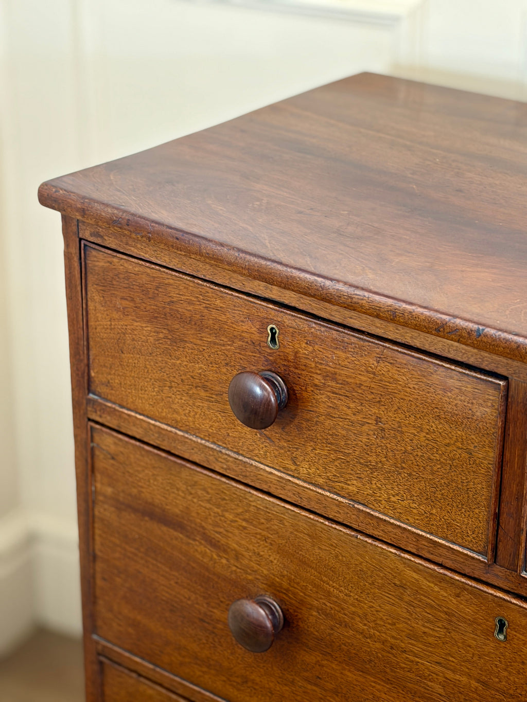 Wooden dresser with two drawers and metal knobs on a plain background