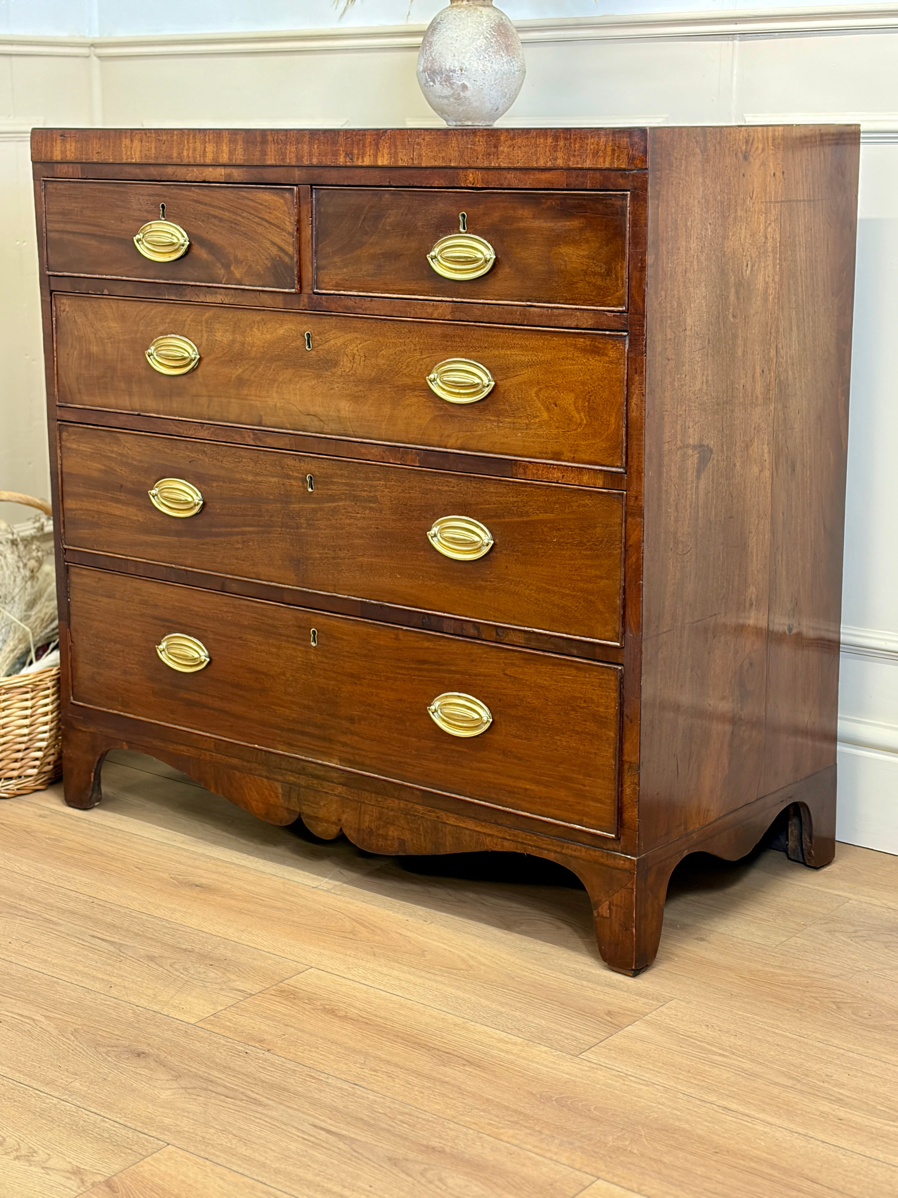 Wooden dresser with gold handles on a wooden floor.