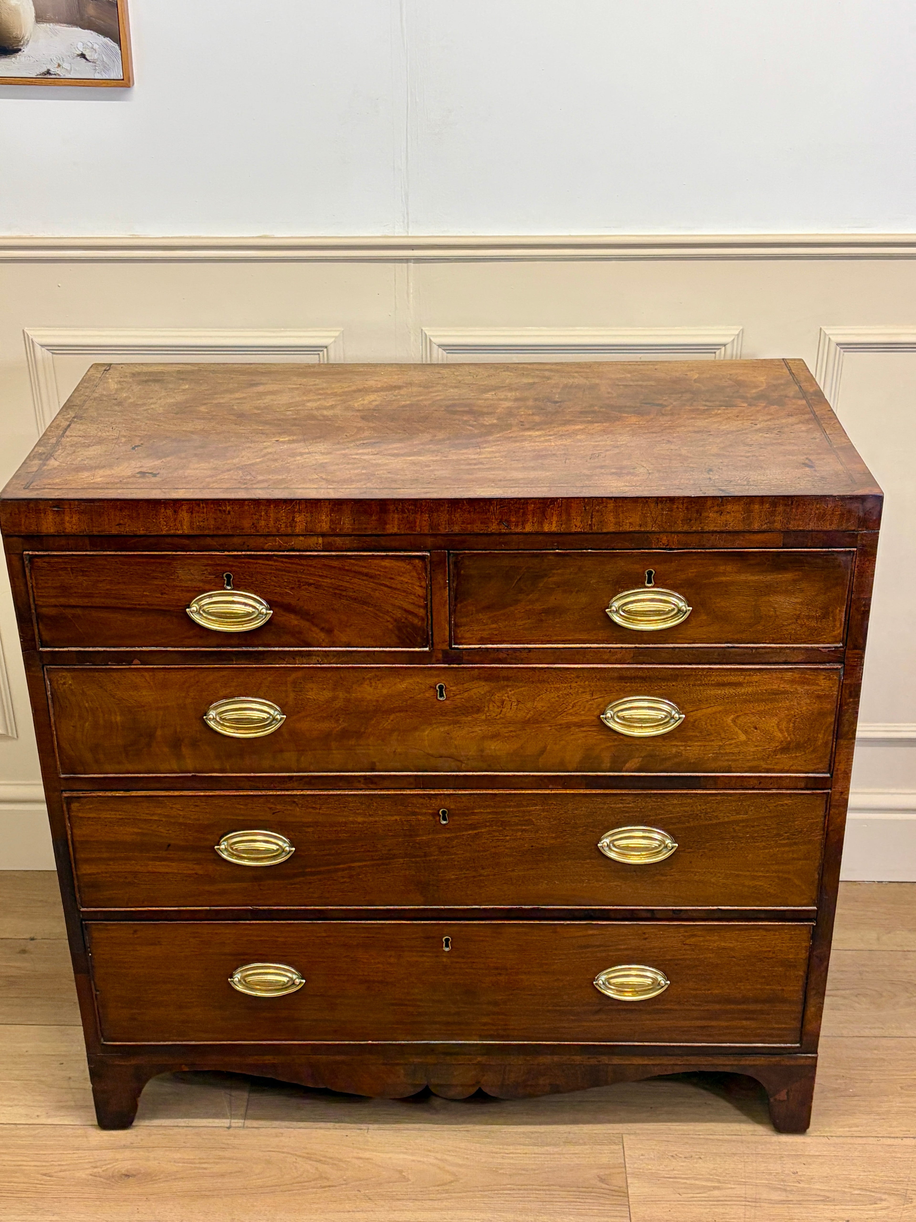 Wooden dresser with brass handles on a wooden floor.