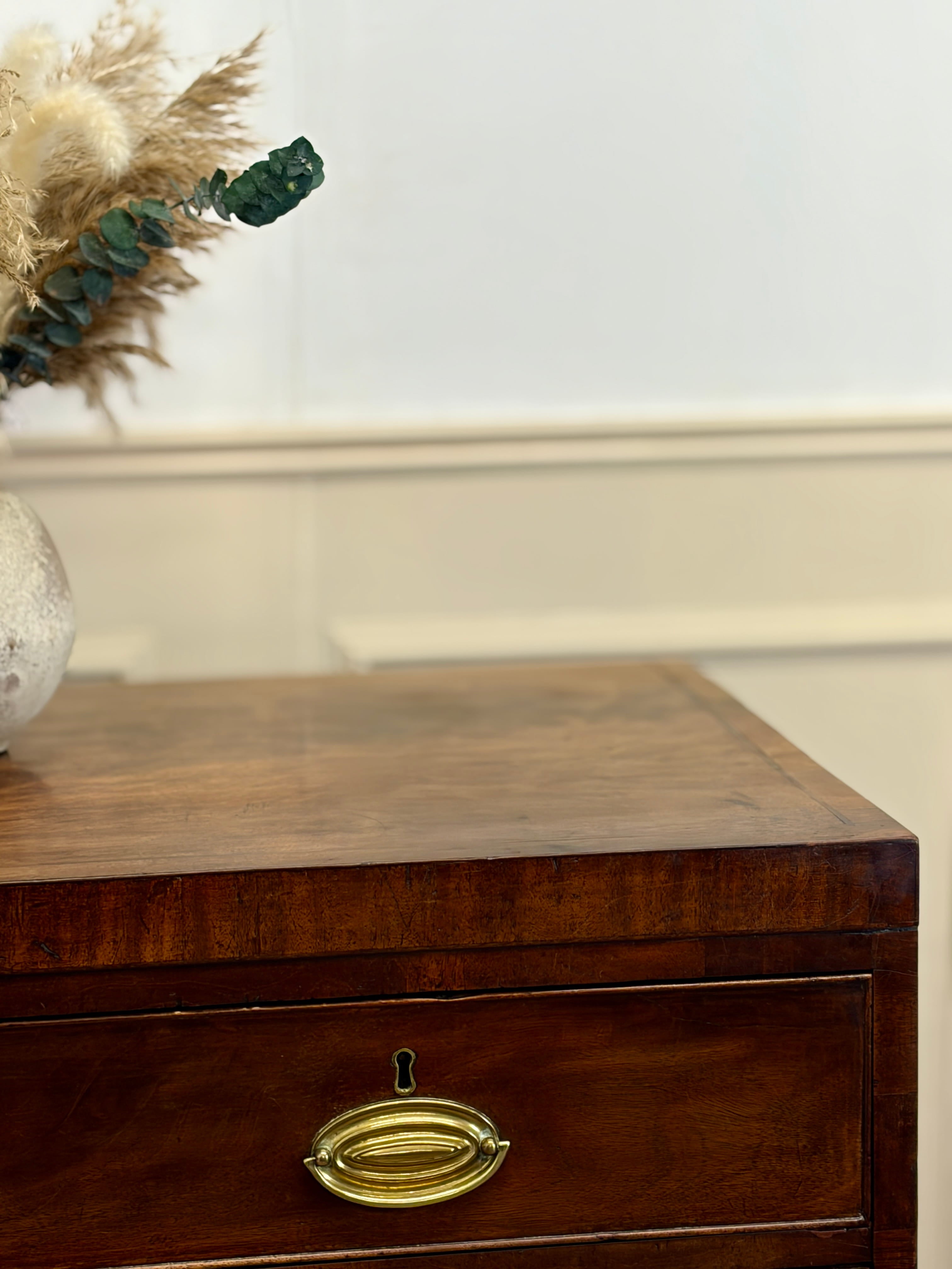 Wooden drawer with brass handle on a white wall background