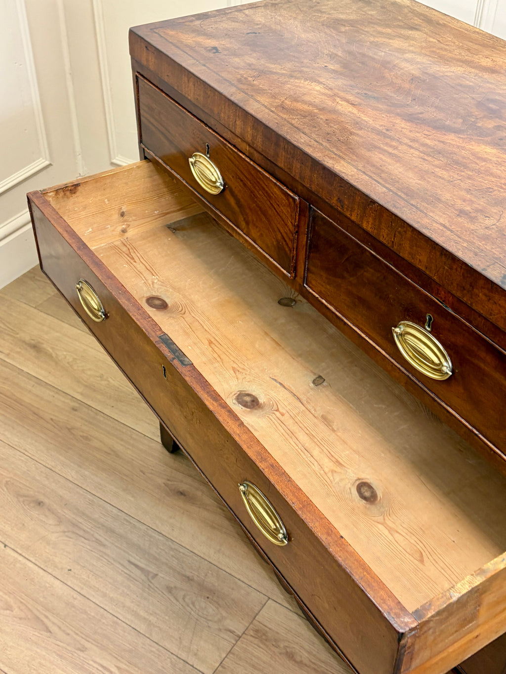 Wooden desk with brass handles on a wooden floor