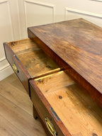 Wooden desk with open drawers against a white paneled wall.
