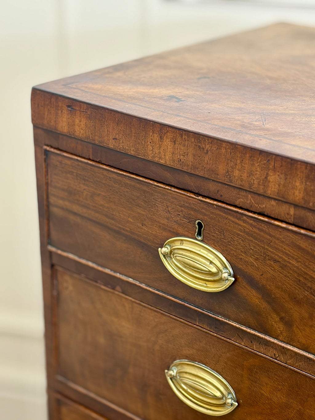 Wooden dresser with brass handles on a plain background