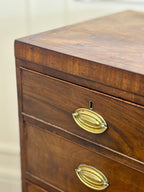 Wooden dresser with brass handles on a plain background