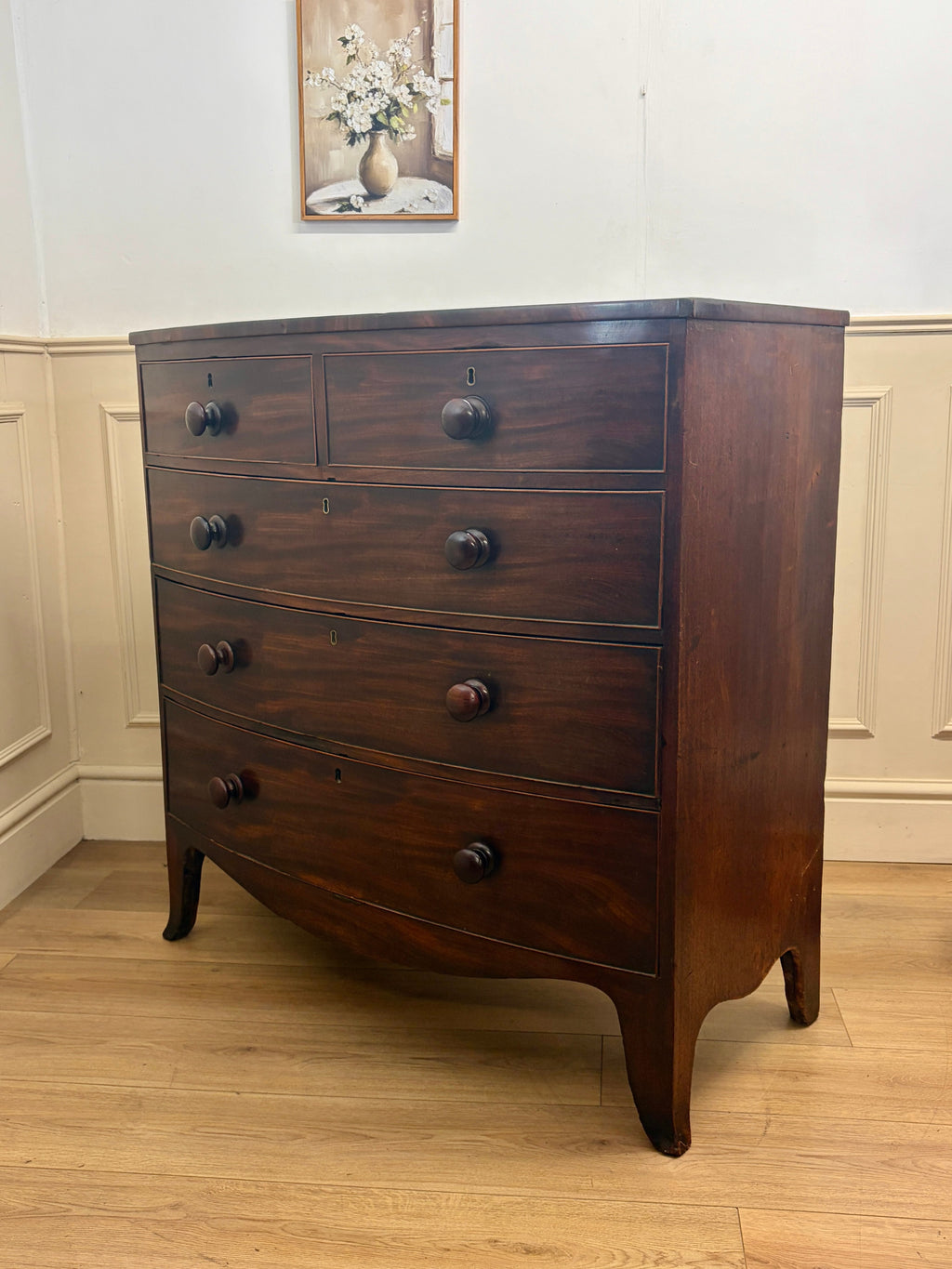 Wooden dresser with four drawers in a room with white walls and a wooden floor.