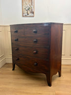 Wooden dresser with four drawers in a room with white walls and a wooden floor.