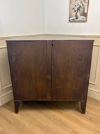 Wooden cabinet with a floral painting on the wall in the background