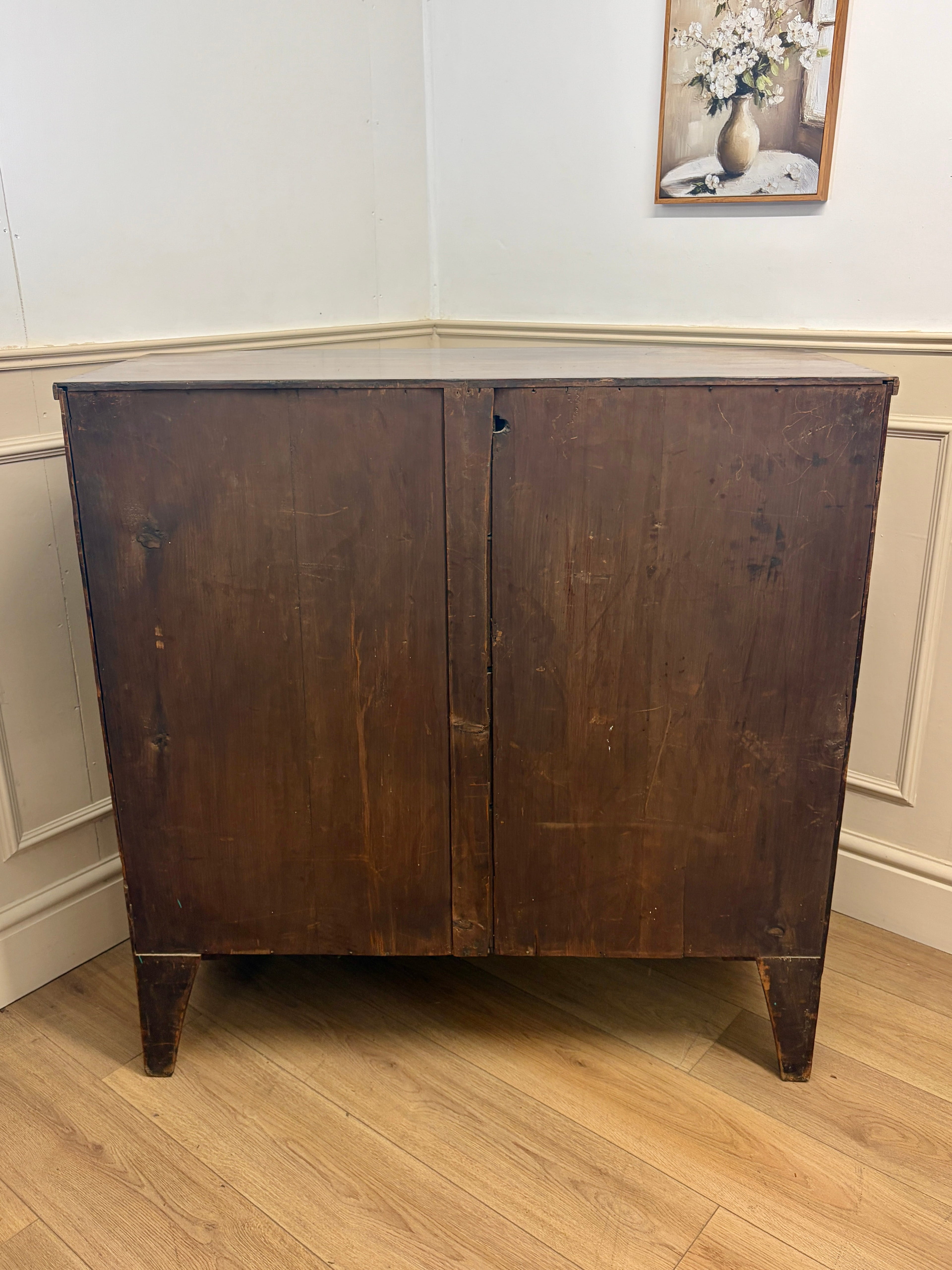 Wooden cabinet with a floral painting on the wall in the background