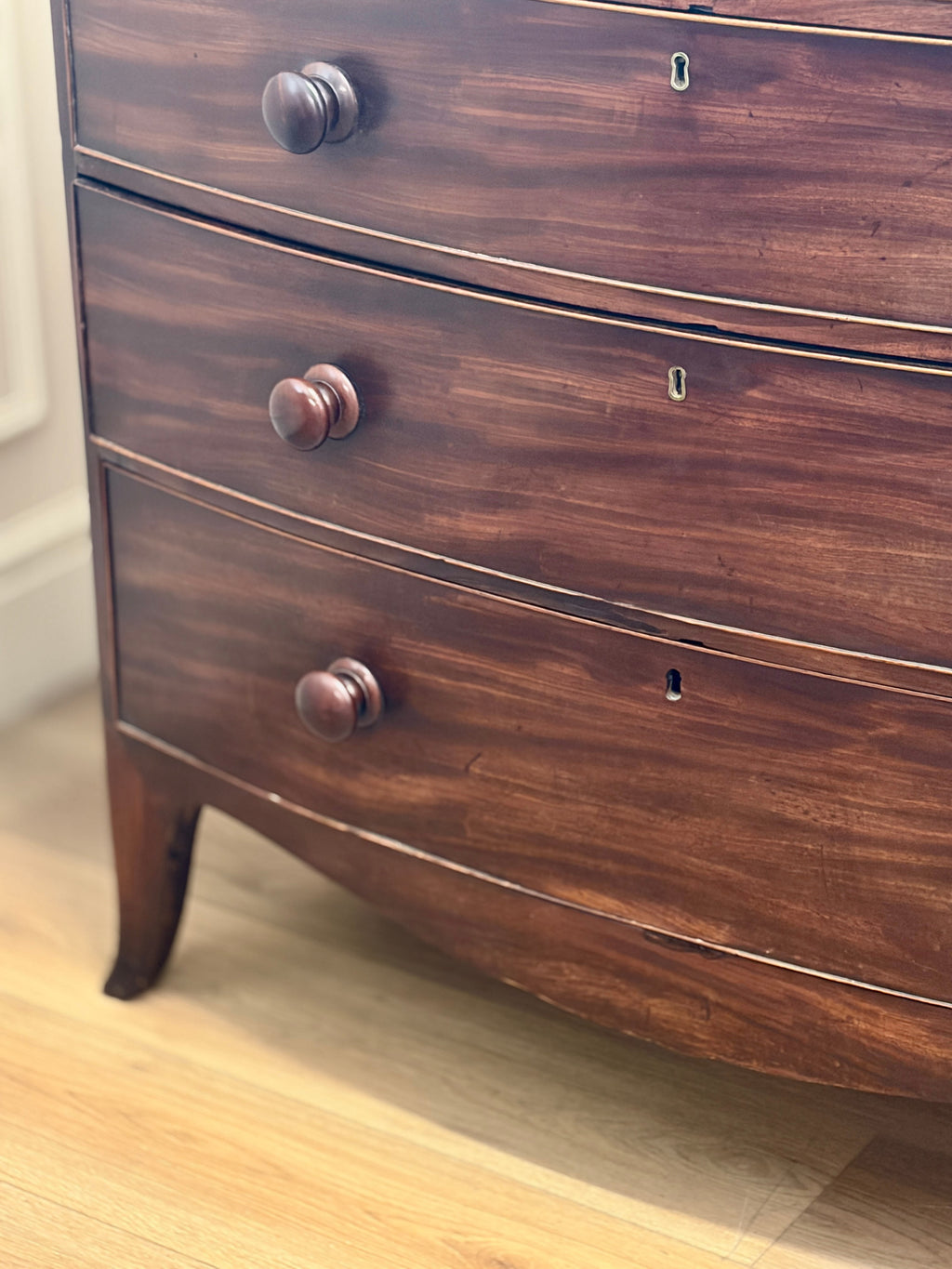 Wooden dresser with three drawers on a wooden floor.