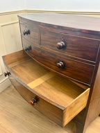 Wooden dresser with curved design and multiple drawers in a room with light-colored walls and floor.
