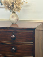 Wooden dresser with a vase of dried plants on top