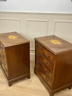 Two wooden dressers with decorative tops against a white paneled wall.