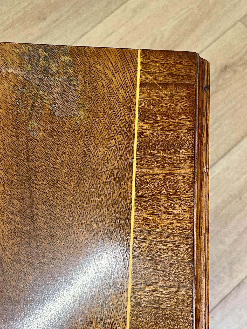 Vintage pair of mahogany bedside chest of drawers with five drawers each, featuring decorative inlaid tops and brass handles, displayed against a cream wall on a wooden floor.