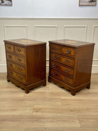 Two wooden dressers with inlaid designs on a wooden floor against a white paneled wall.