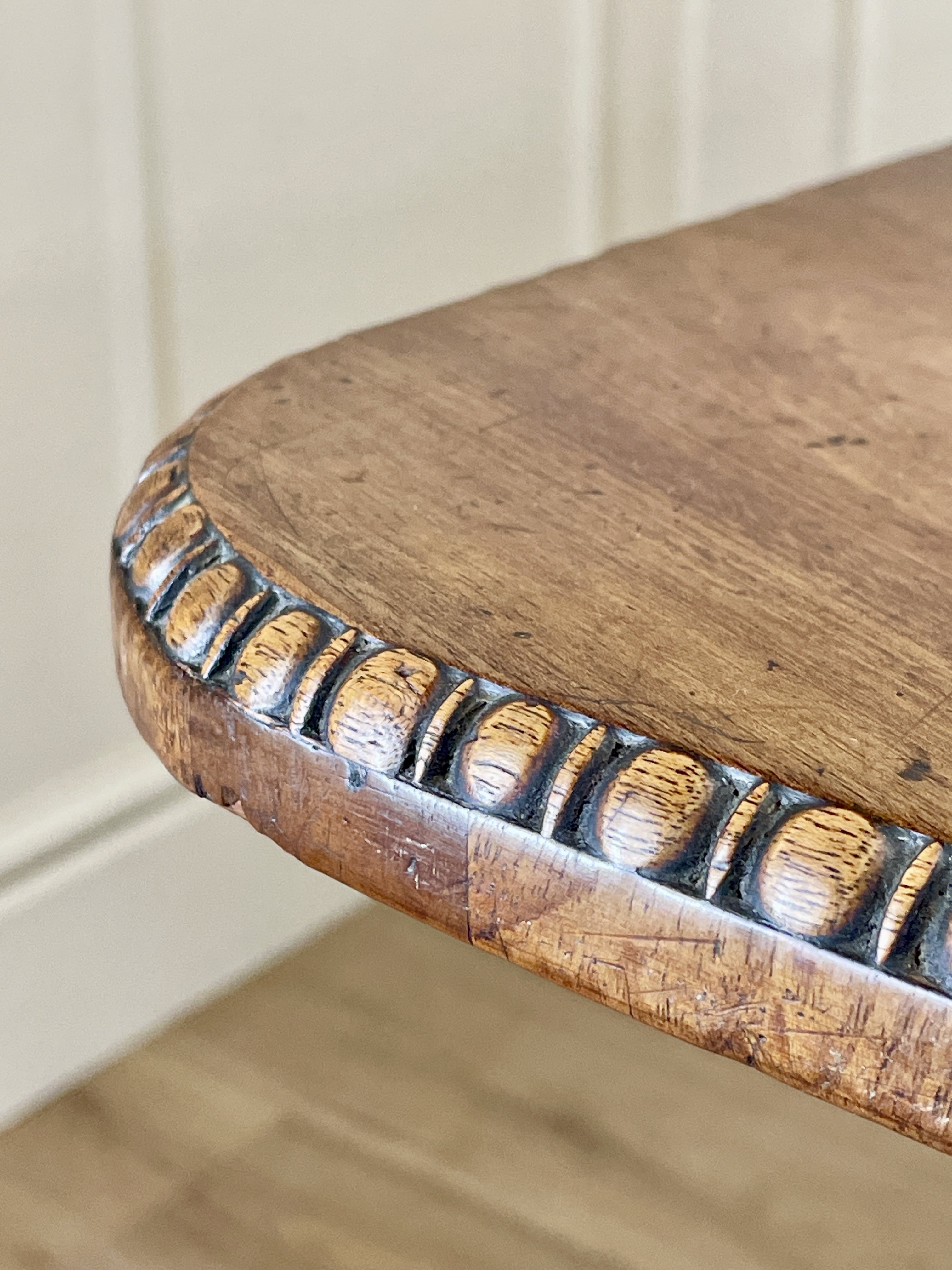 Close-up of a wooden stool with decorative edge on a neutral background